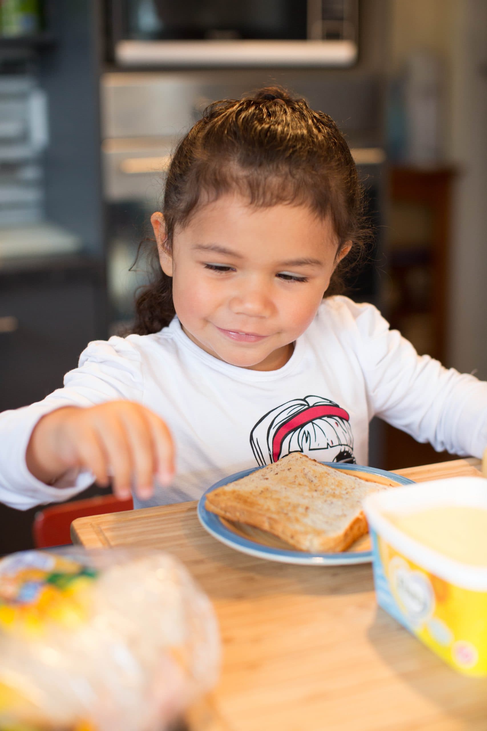 Young client, Marama sits at a table eating breakfast