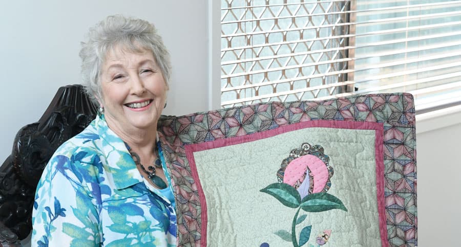 Client Jenny sits proudly holding a beautiful quilt that she has made