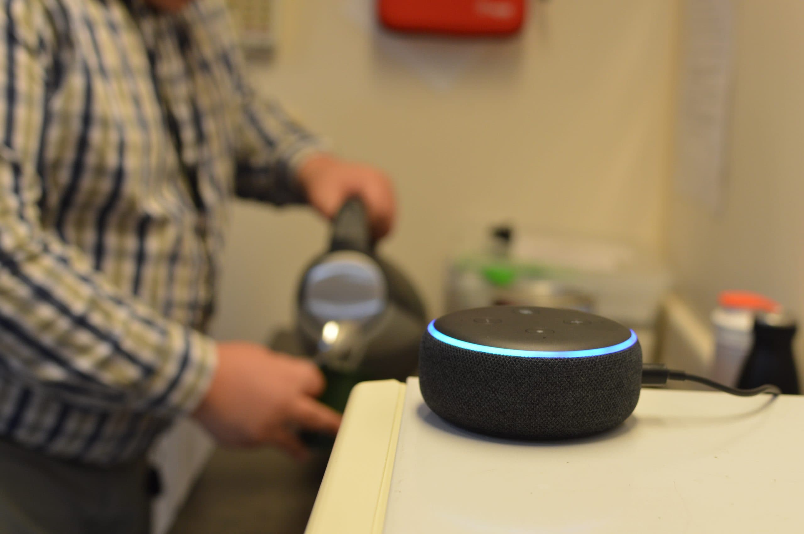 A male client makes a cup of tea while listening to his Alexa