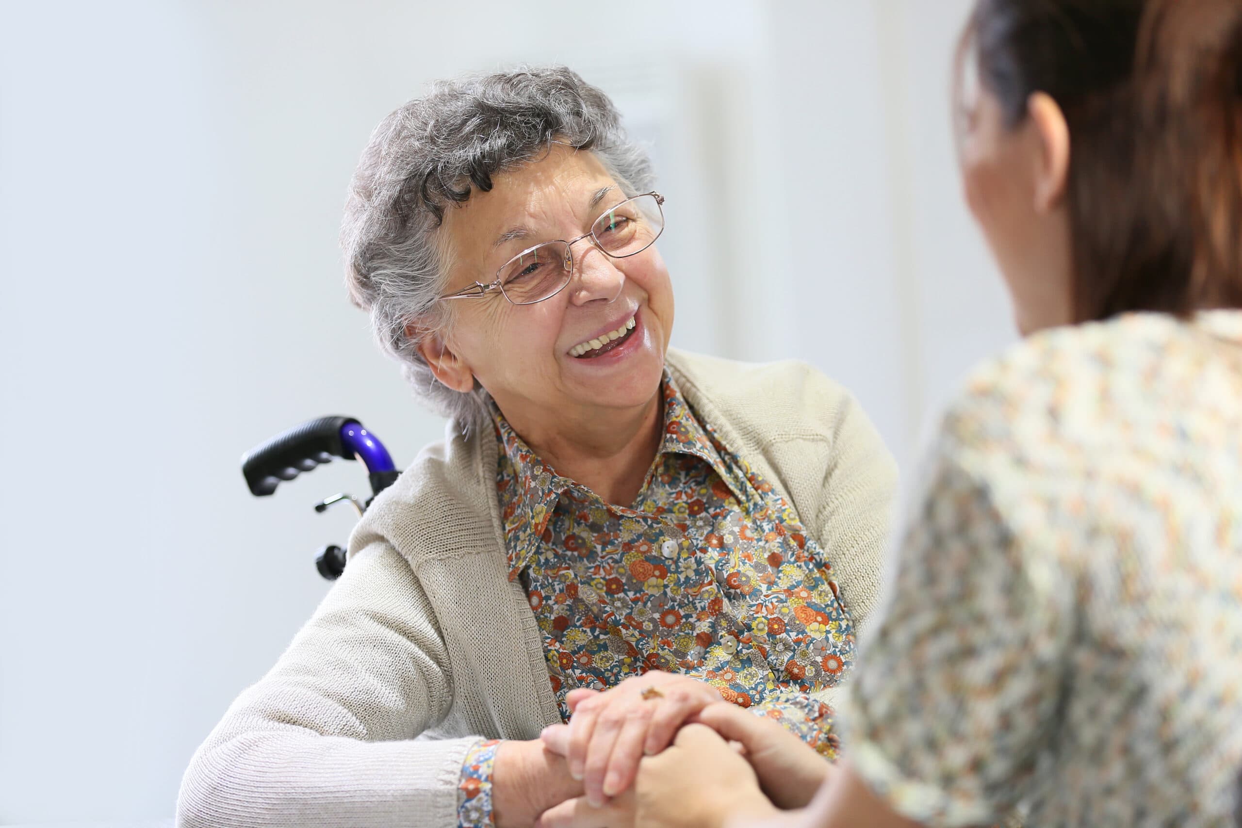 An elderly client in a wheelchair is comforted by a younger woman