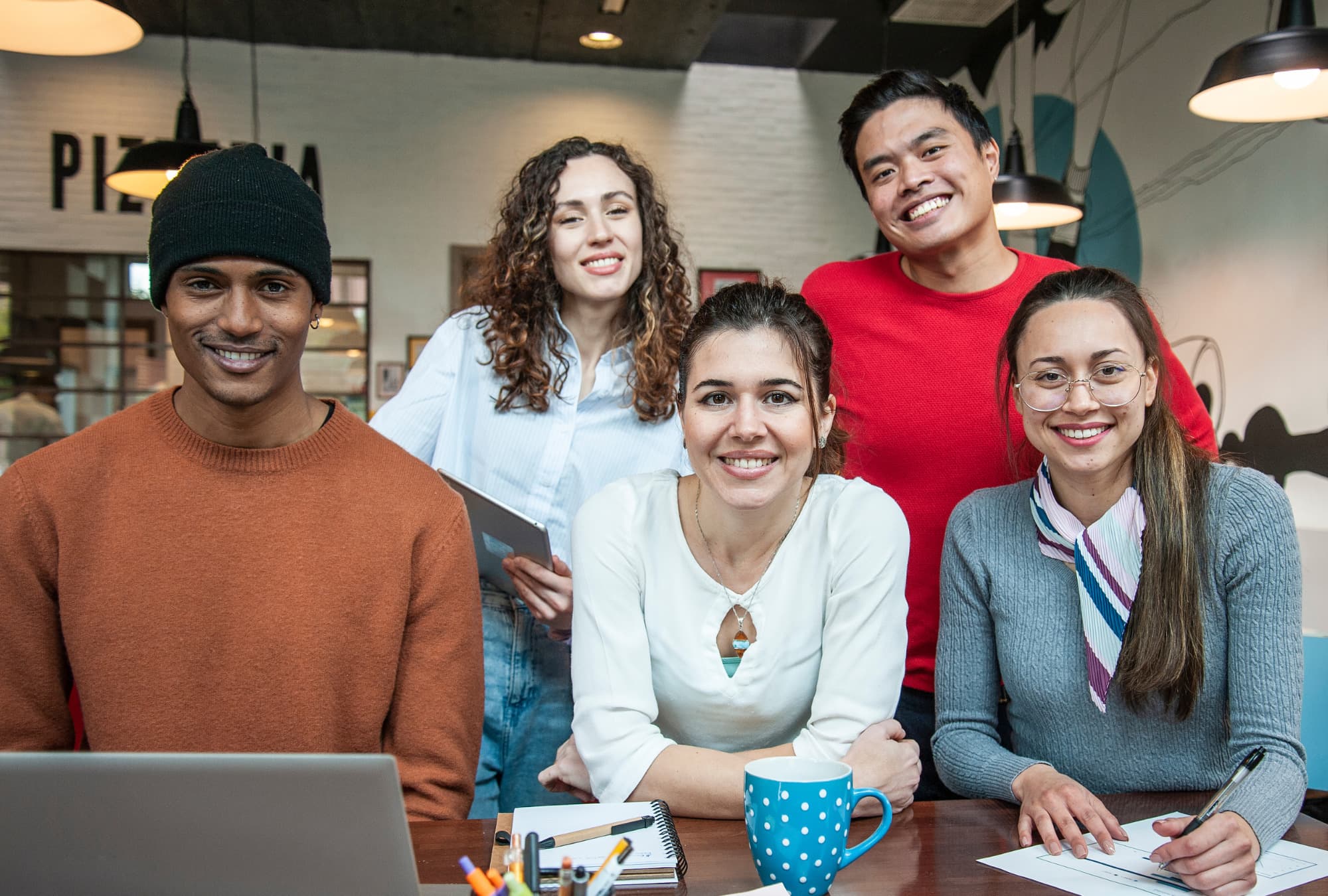 A group of young people sit facing the camera and smiling.