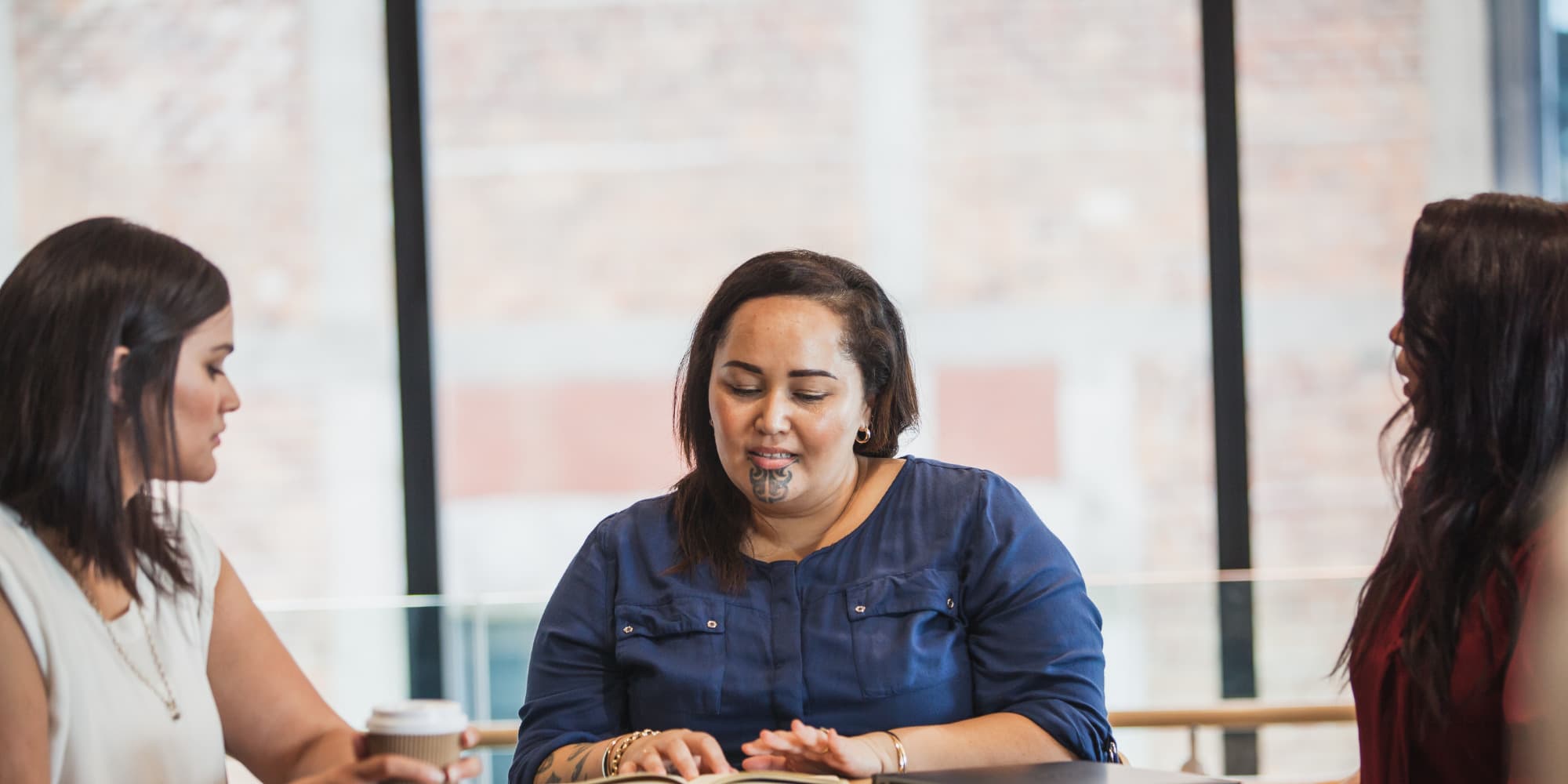 A Māori woman reading braille