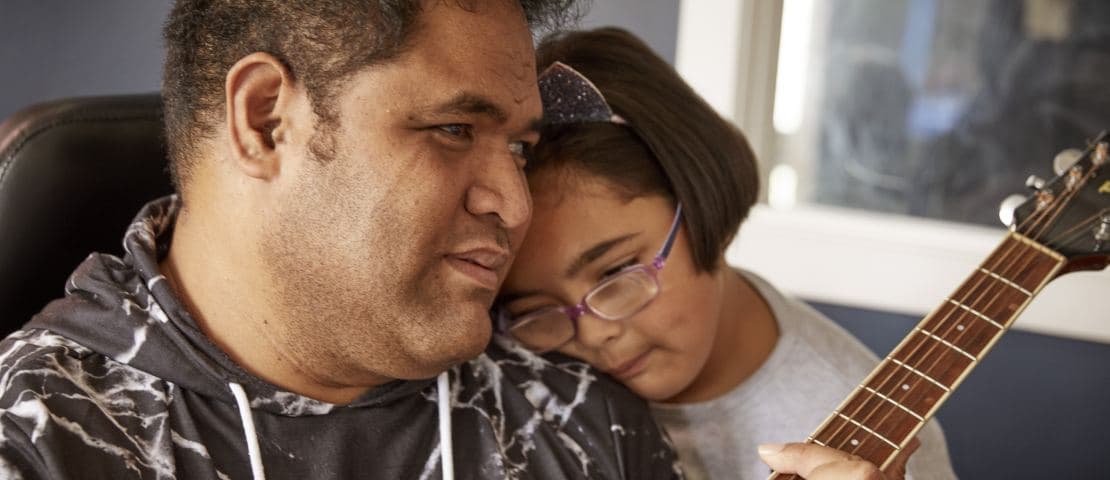 Ese playing his guitar with his daughter on his shoulder