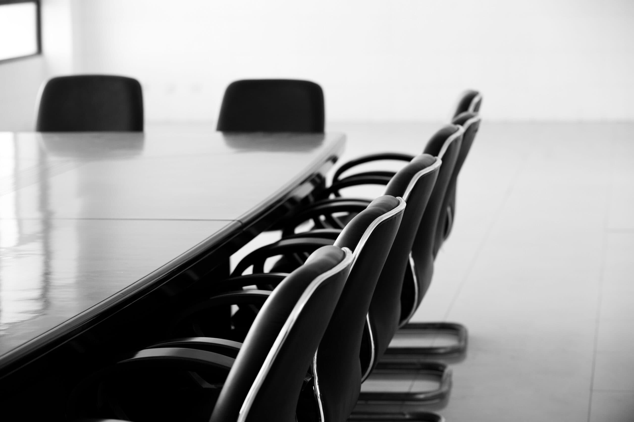 An empty boardroom table with chairs around the outside