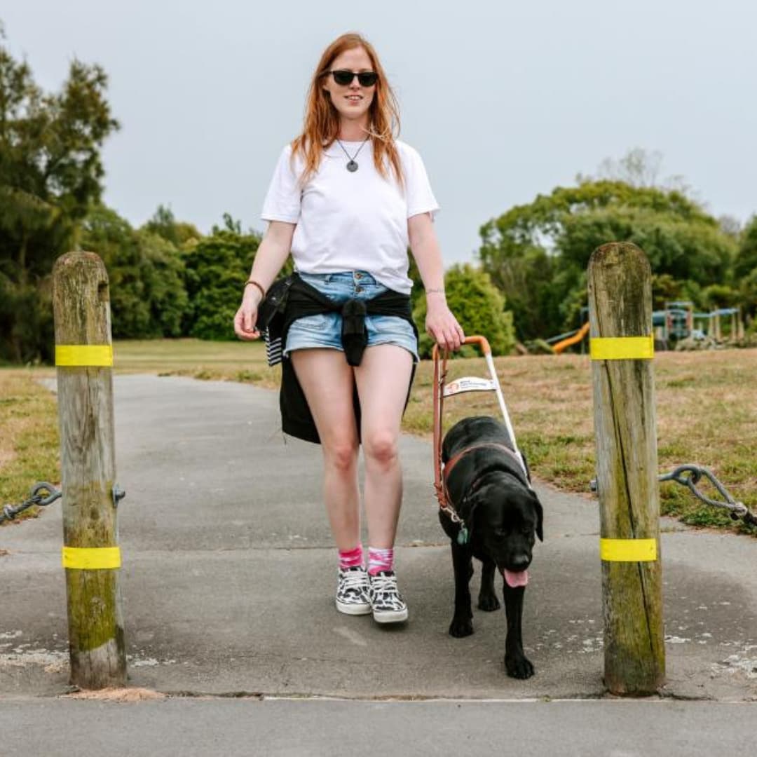 Blind Low Vision NZ member Laura and her dog Ryder taking a walk outside.