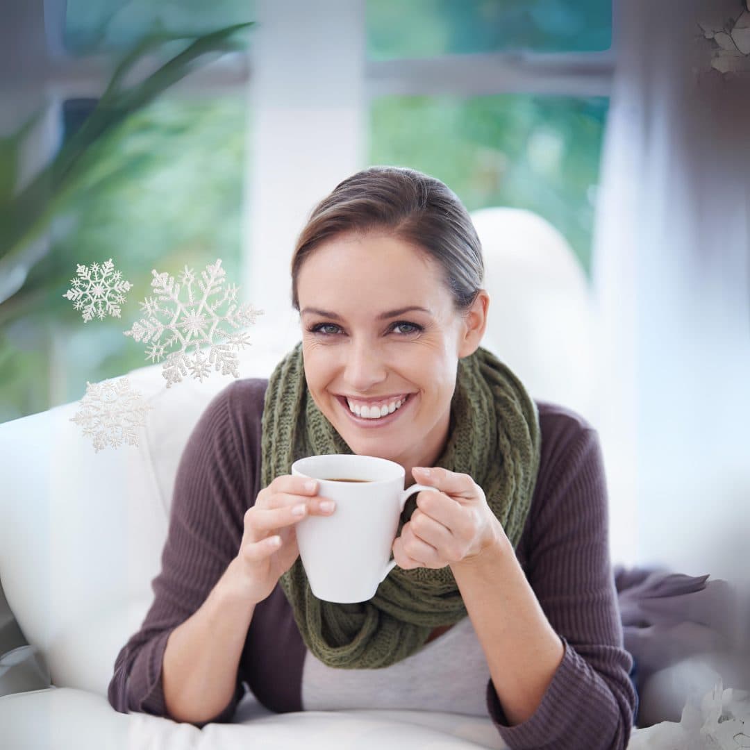 A woman inside on a cold winter's day, enjoying a hot drink.
