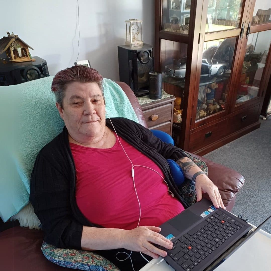 Sue sitting in a chair with a laptop.