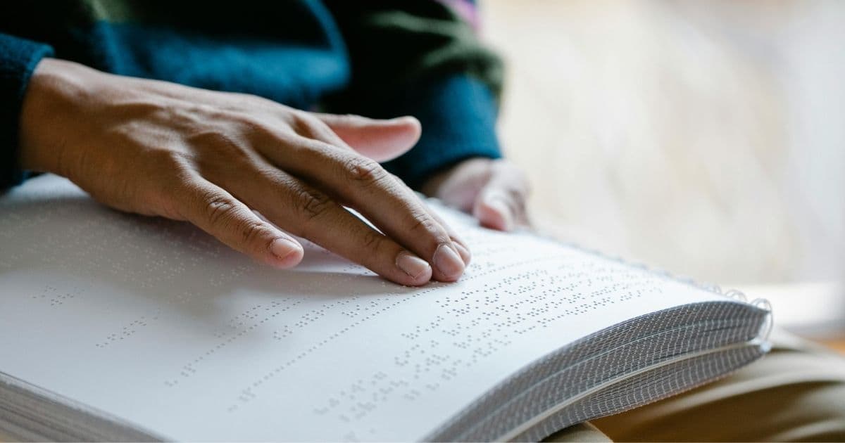 A close up of a person's hand reading Braille.