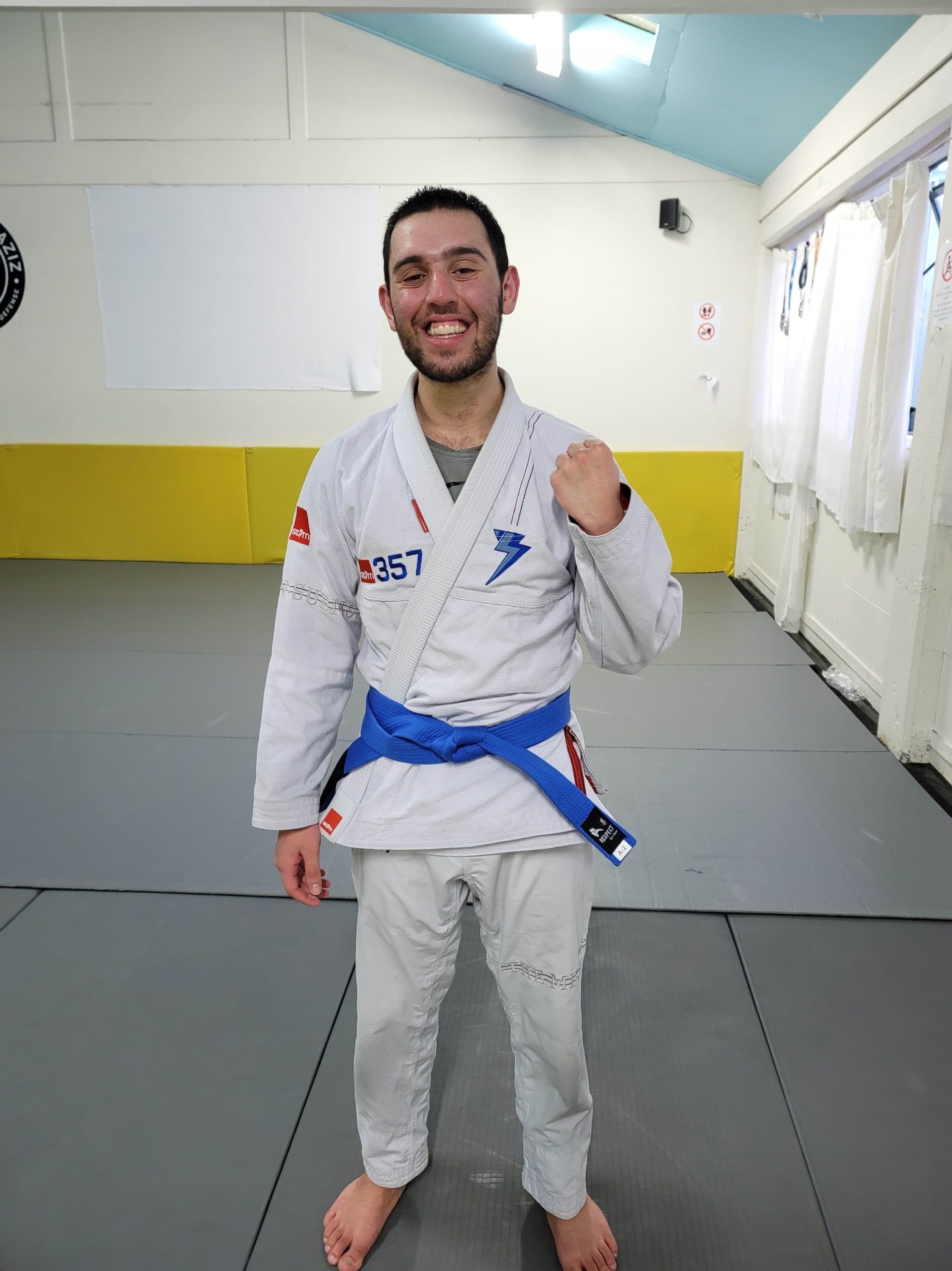 Tasal is smiling at the camera. He is wearing his white mixed martial arts uniform with a blue belt.