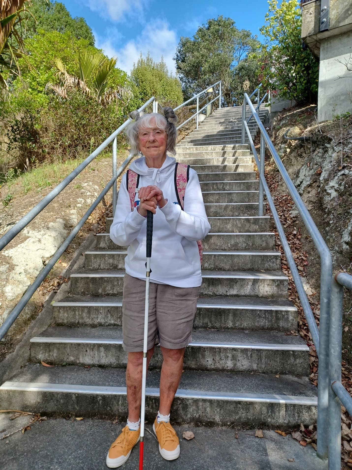 A woman standing at the bottom of a large flight stairs.
