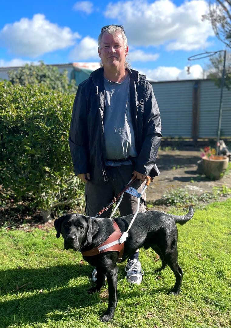 A man and his guide dogs standing in a garden.
