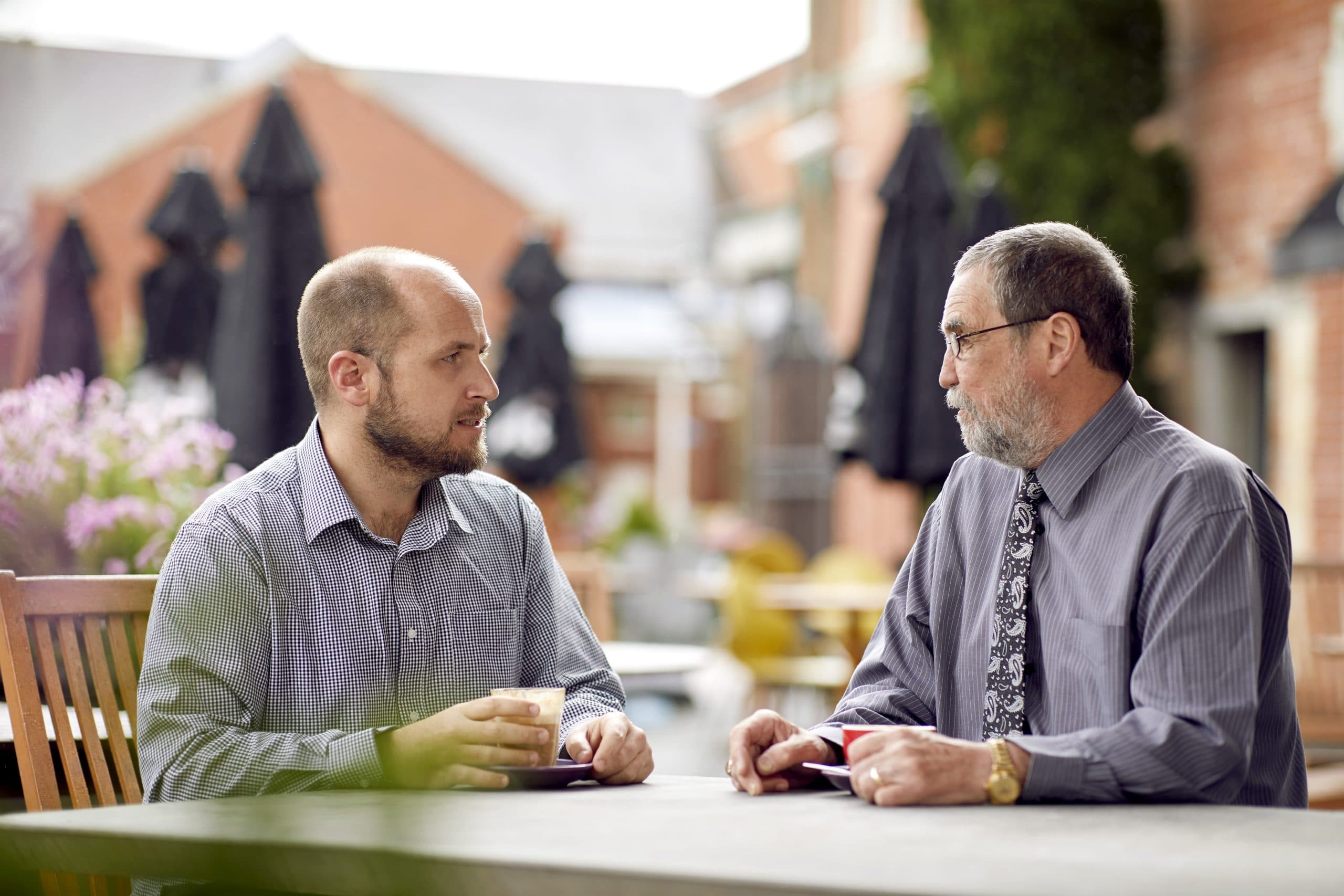 Two male clients sit outside at a table