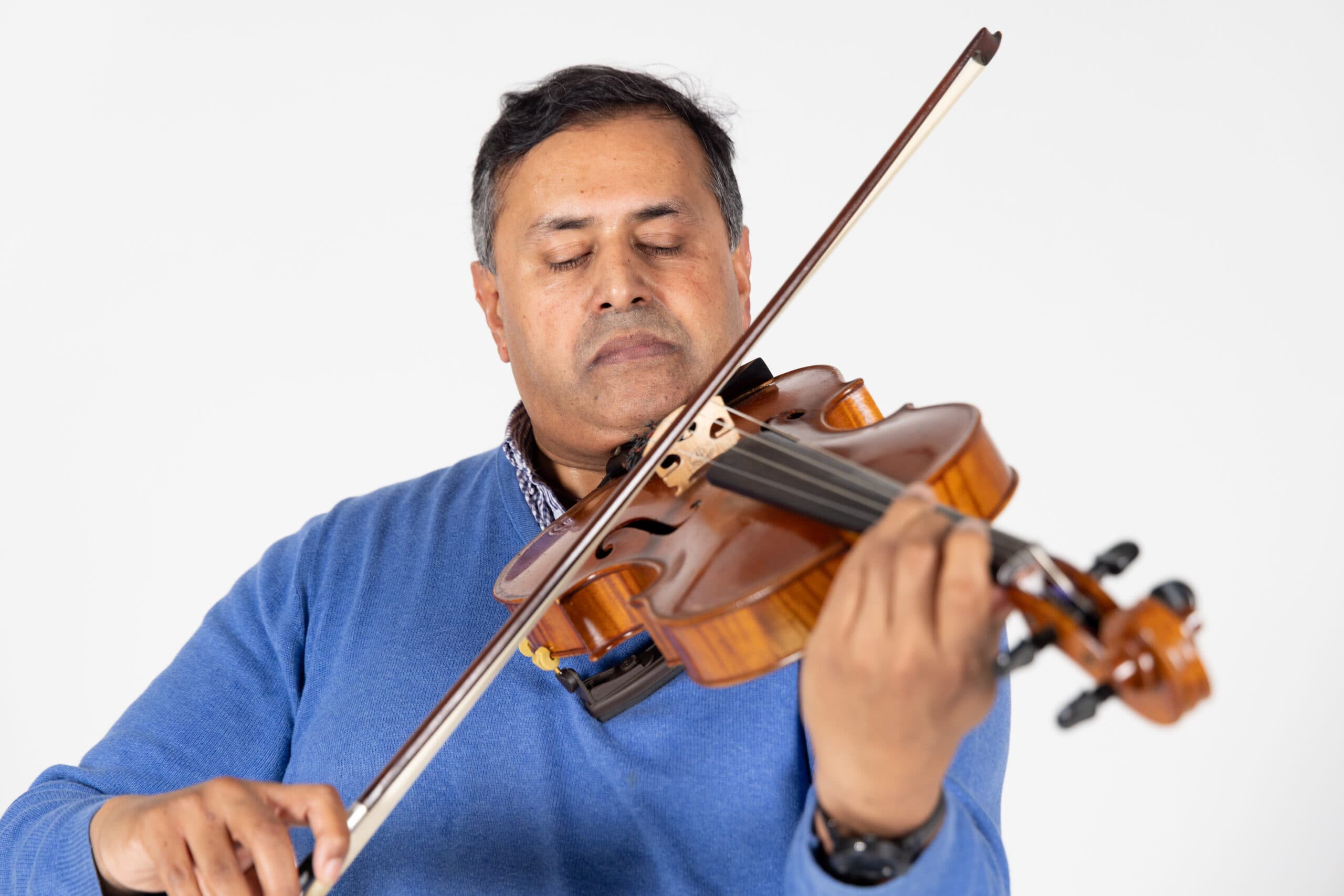 Client David is playing the violin, he has his eyes closed as he plays