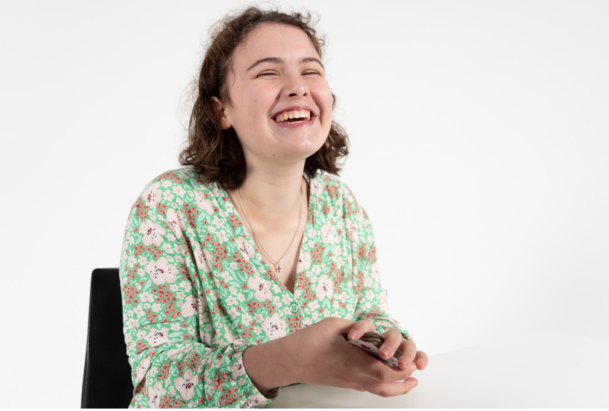 Client Imogen is sitting down and laughing while holding a pack of cards
