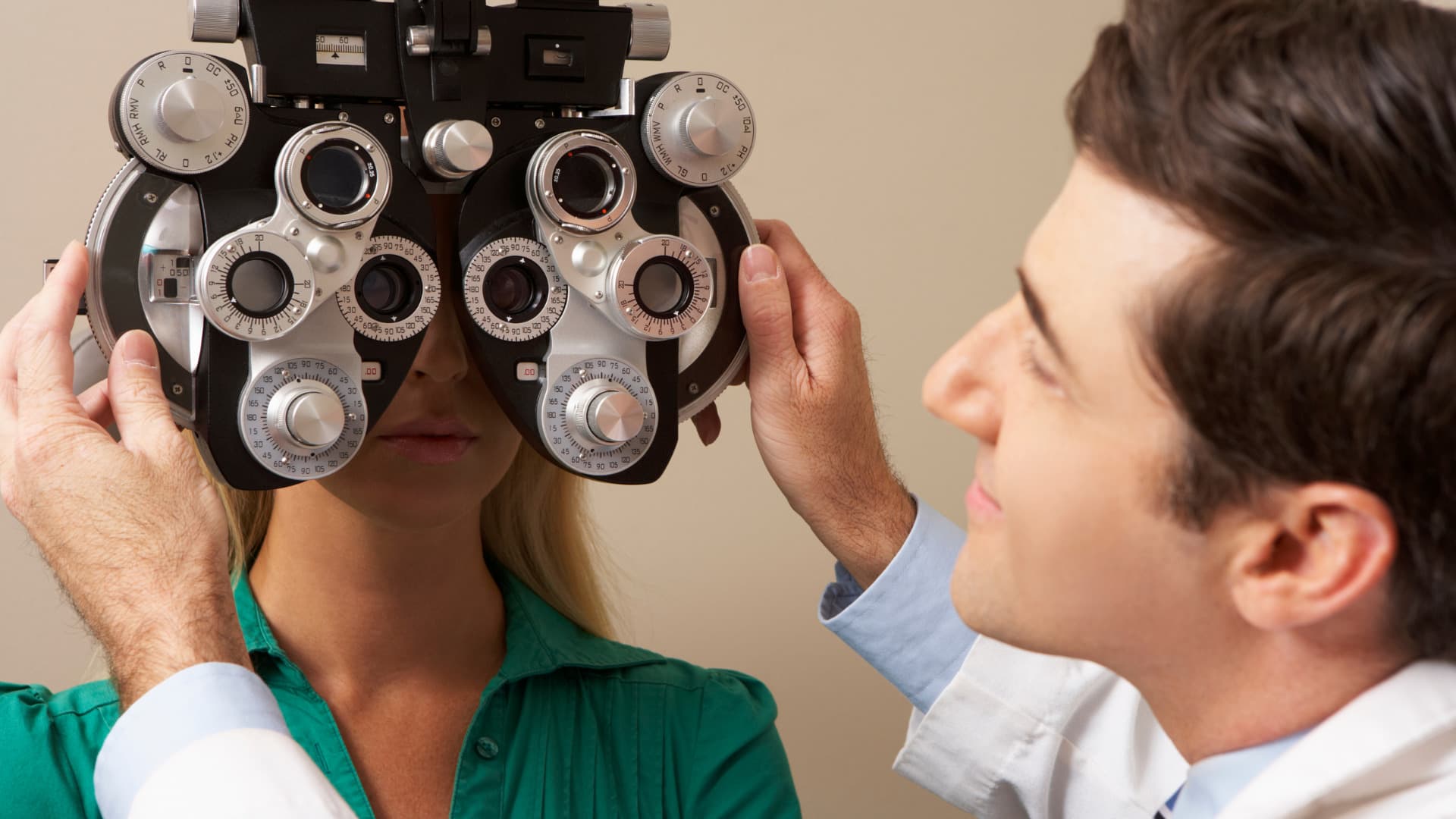 A male optometrist is giving a young woman an eye test