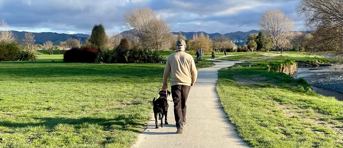 Andy walks safely alongside his guide dog, Granger who is a black Labrador retriever.