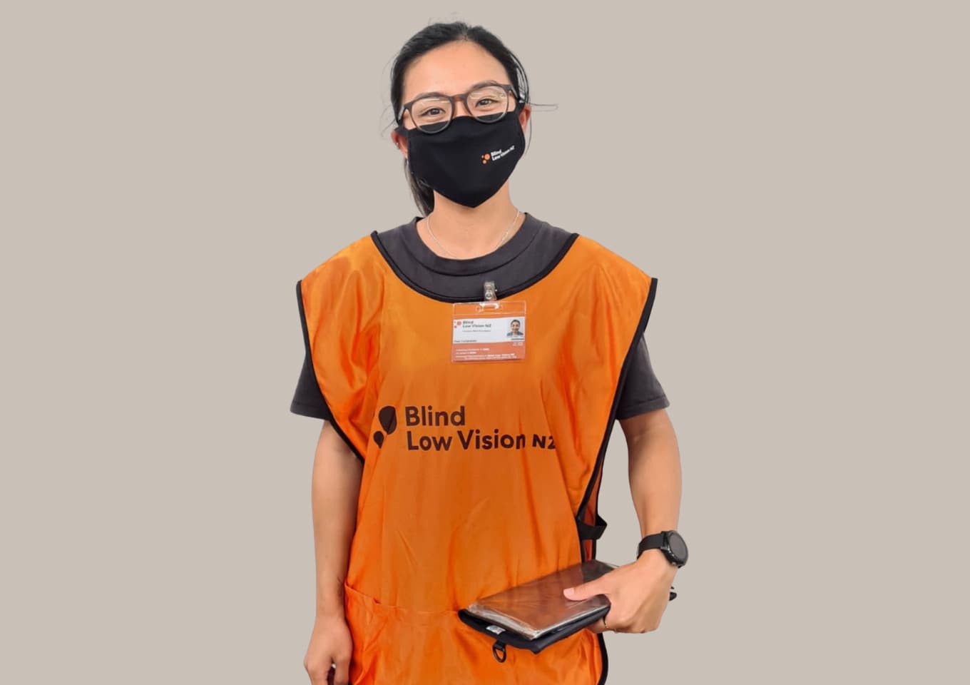 Face to face fundraiser, with their mask on, wearing their orange vest and ID.