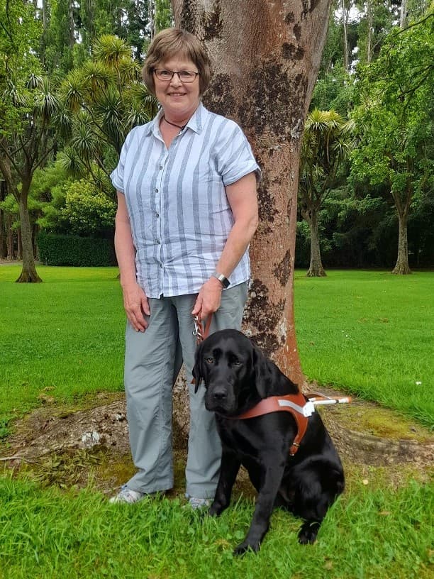 Robyn stands with her guide dog, a shiny black Labrador named Holly.