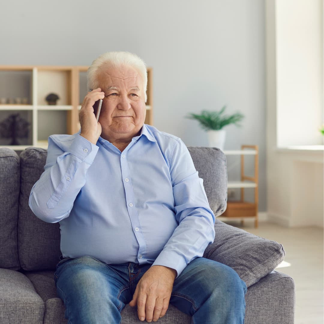 A mature man chats on the phone in his living room.